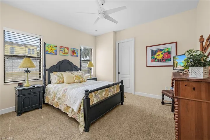 Carpeted bedroom featuring multiple windows with blinds, a ceiling fan, and a solid core door