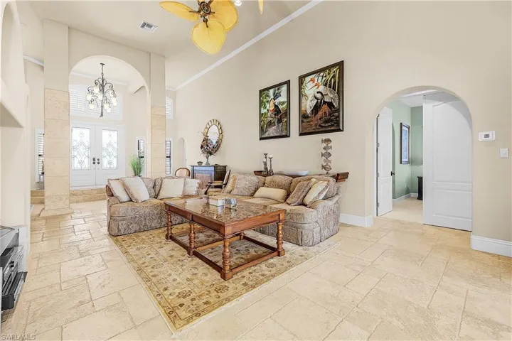 Spacious living area featuring high vaulted ceilings, large format tile flooring, and decorative arched doorways