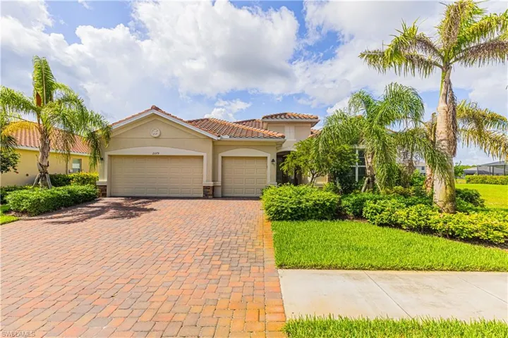 Mediterranean / spanish house with an attached garage, a front yard, decorative driveway, and stucco siding