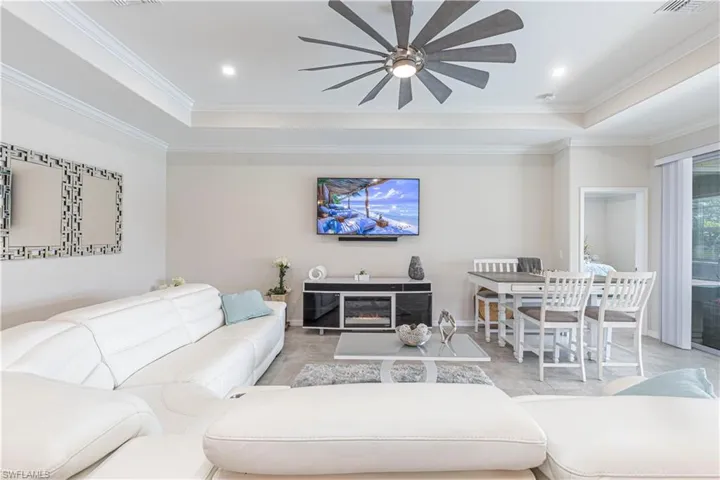 Living area with a tray ceiling, ornamental molding, and ceiling fan