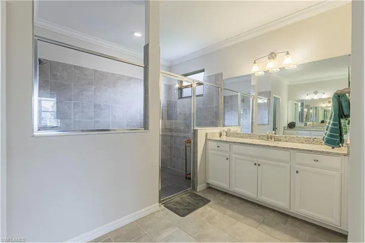 Full bathroom featuring vanity, a stall shower, crown molding, and light tile patterned flooring