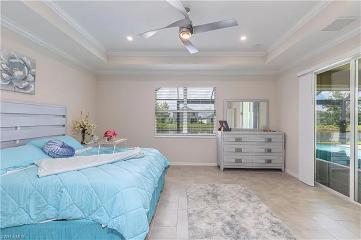 Bedroom with access to exterior, ceiling fan, a tray ceiling, and crown molding