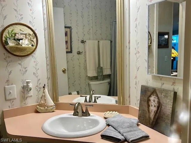 Bathroom with wallpapered walls and vanity