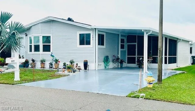 Rear view of property featuring an attached carport, driveway, a yard, and a sunroom