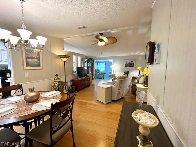 Dining space featuring bamboo wood-style flooring, a chandelier, a textured ceiling, and ceiling fan
