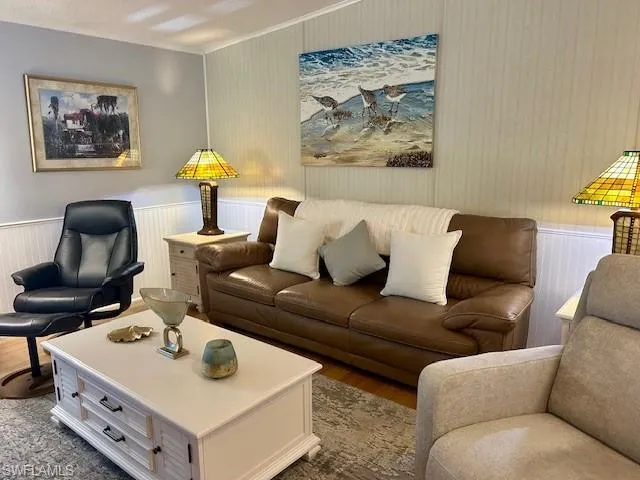 Living room with bamboo wood-style floors, a wainscoted wall, and ornamental molding