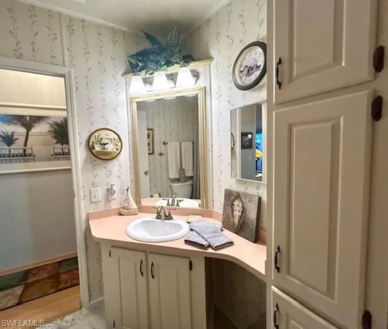 Bathroom featuring wallpapered walls and vanity