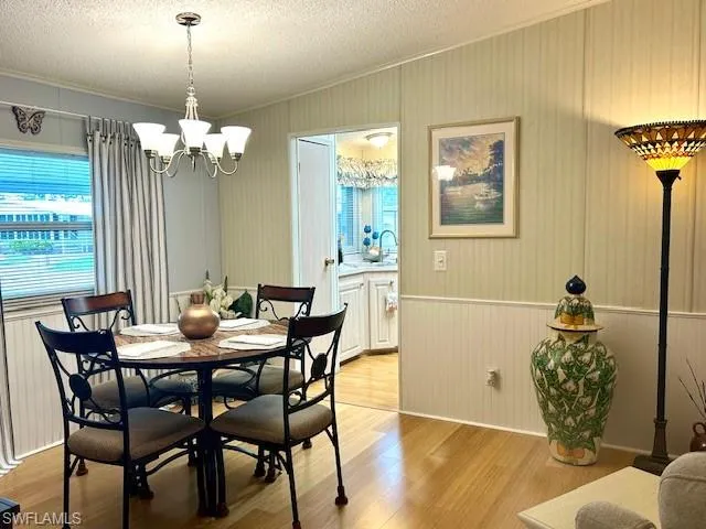 Dining room with bamboo wood-type flooring, a chandelier, ornamental molding, and a textured ceiling