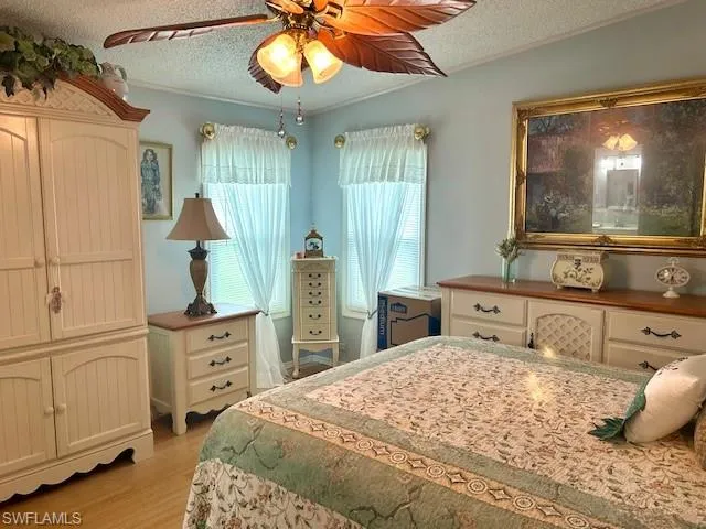 Bedroom with bamboo wood finished floors, a textured ceiling, crown molding, and ceiling fan