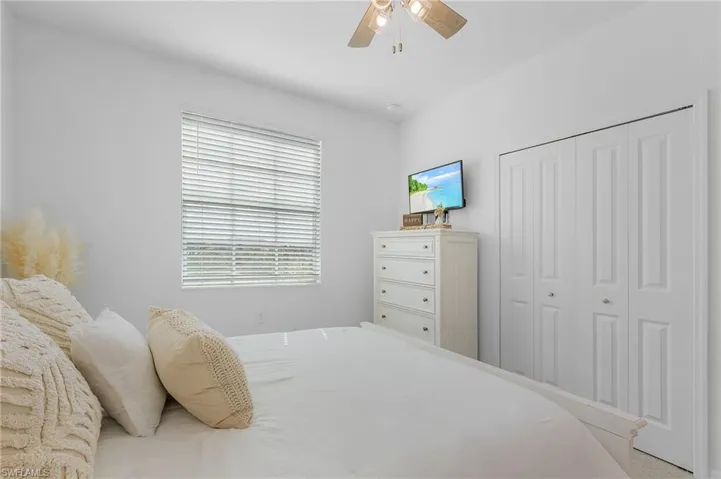 Carpeted bedroom featuring ceiling fan and a closet