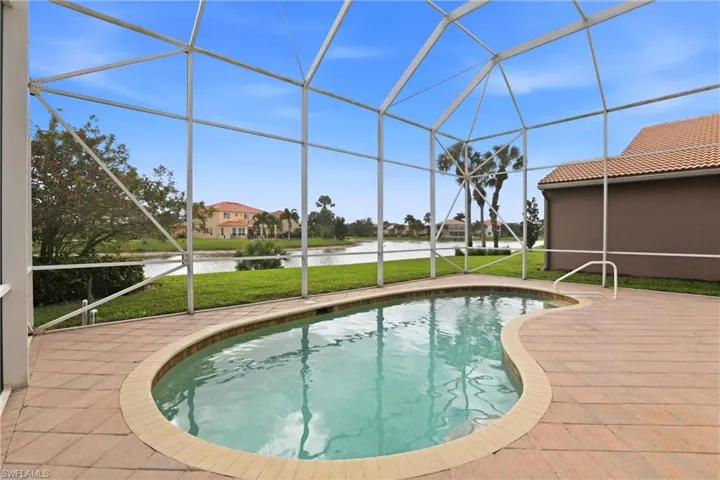 Swimming pool with a sunroom, glass enclosure, a water view, and a yard