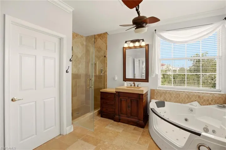 Full bathroom with a shower stall, vanity, a whirlpool tub, ornamental molding, and ceiling fan