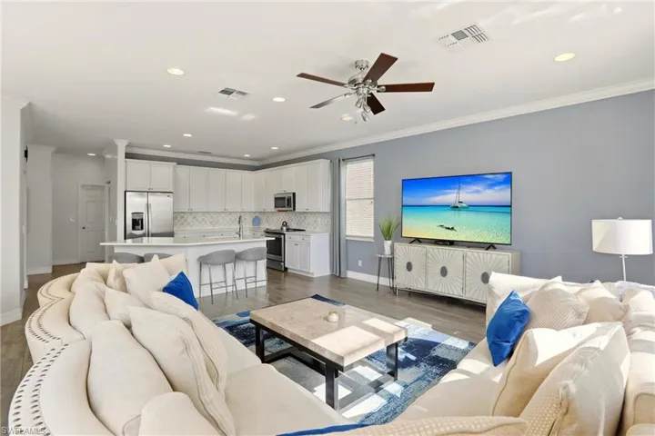 Living room with ornamental molding, recessed lighting, ceiling fan, and wood finished floors