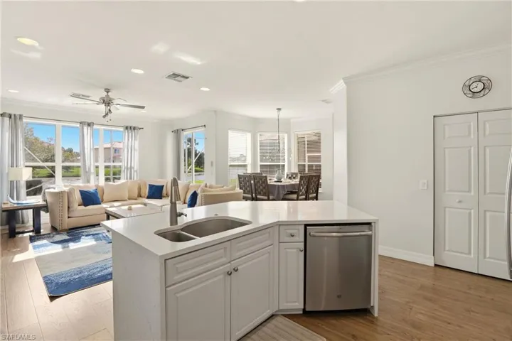 Kitchen with white cabinetry, light stone countertops, dishwasher, light wood-style flooring, and open floor plan