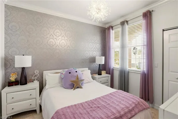 Bedroom with wallpapered walls, crown molding, and a chandelier