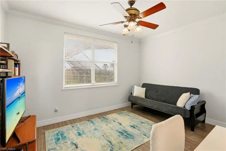 Living area with ornamental molding, wood finished floors, and a ceiling fan