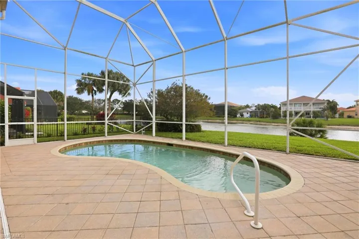 Outdoor pool with glass enclosure, a sunroom, a water view, a yard, and a patio