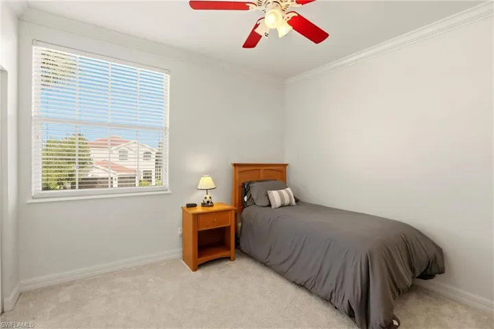 Carpeted bedroom featuring ornamental molding and a ceiling fan