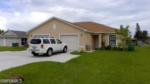 Single story home featuring stucco siding, a front lawn, driveway, and an attached garage