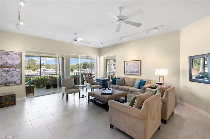 Spacious living area featuring large format tile flooring, multiple ceiling fans, and track lighting