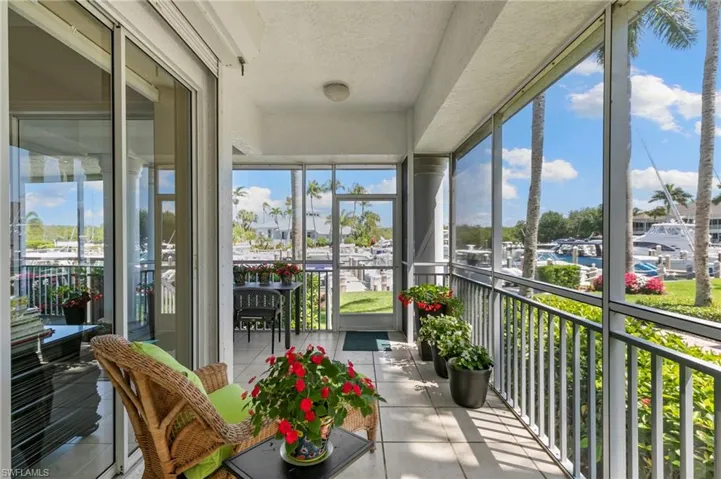 Screened balcony with tiled flooring, sliding glass doors, and marina views