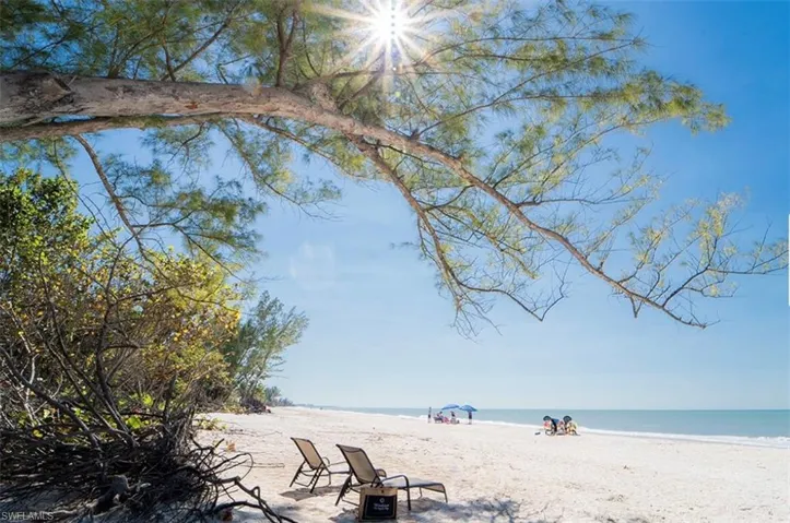 Expansive sandy beach with clear blue water and a bright sky
