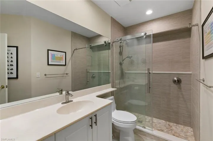 Contemporary bathroom featuring a spacious glass-enclosed shower with pebble-finish flooring and a wall-mounted showerhead