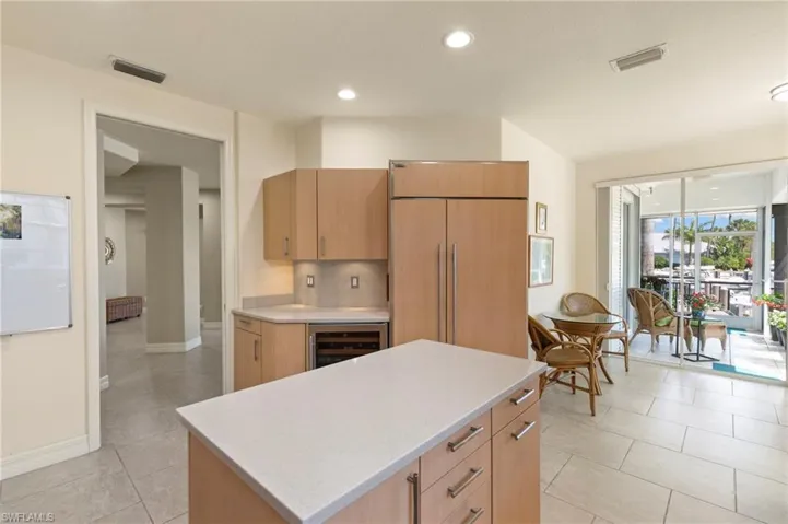 Kitchen featuring light wood cabinetry, white stone countertops, integrated paneled refrigerator, and a built-in wine cooler