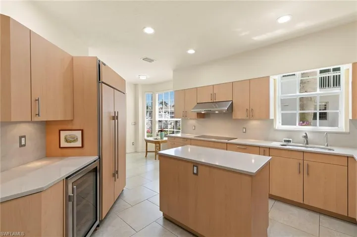 Bright kitchen featuring ample wood-finish cabinetry, light countertops, and a central island