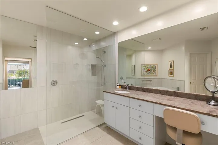 Spacious bathroom featuring a glass-enclosed shower with tiled walls and a linear drain