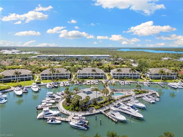 Aerial perspective showcasing a vibrant marina with numerous boats docked, surrounded by lush landscaping and residential buildings