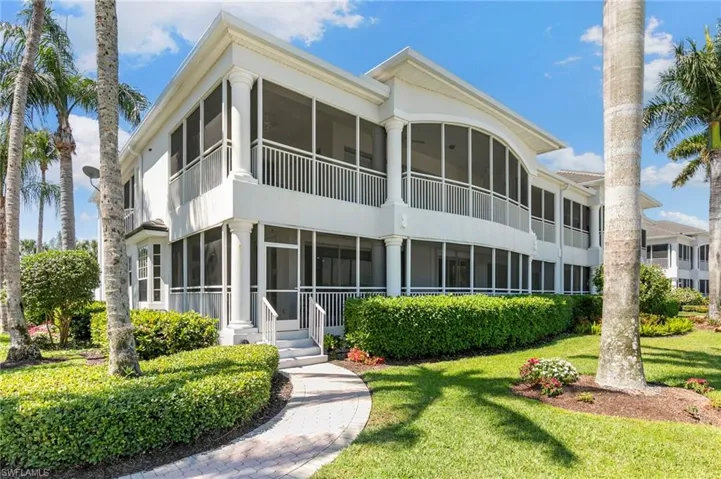 Two-story white exterior with multiple screened balconies and patios
