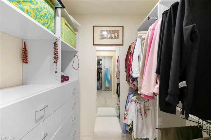 Walk-in closet featuring built-in shelving, integrated drawers with metal pulls, ample hanging space, and a full-length mirror