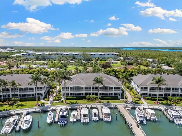 Waterfront condominium community featuring a private marina with multiple boat slips, screened balconies, and lush tropical landscaping