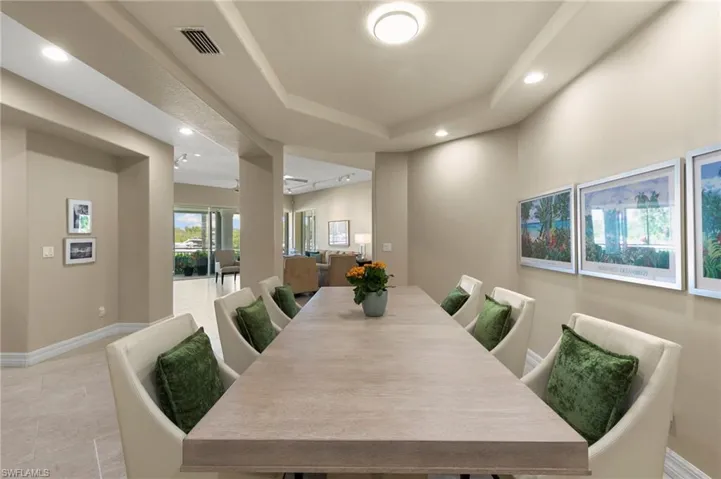 Spacious dining area featuring a tray ceiling with recessed lighting, tile flooring, and a large dining table with seating