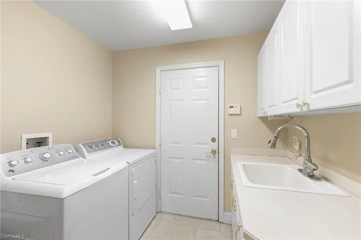 Utility room featuring light-toned walls, tile flooring, and a service door