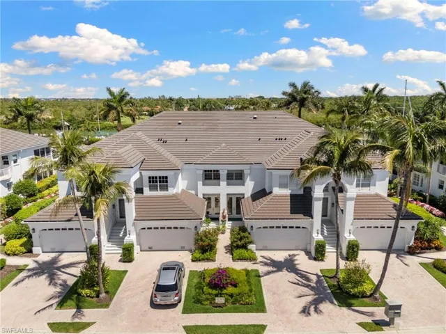 Two-story residential structure featuring a tile roof, white exterior finish, multiple attached garages, and a paved driveway