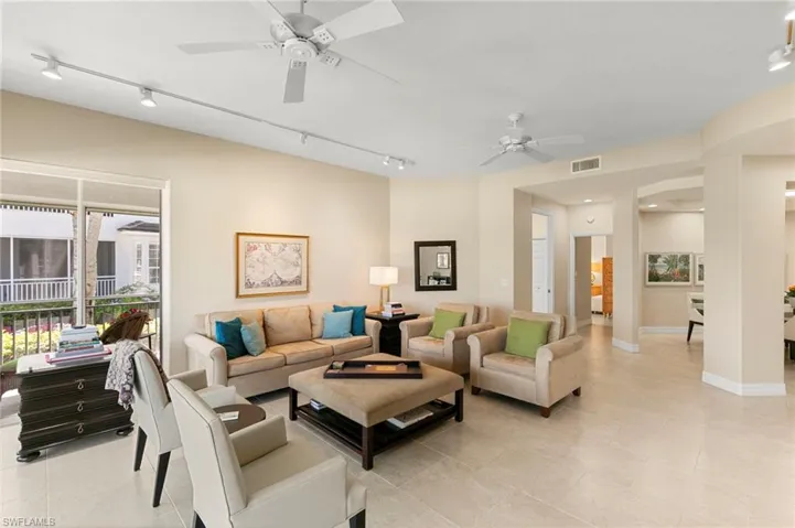 Spacious living area featuring neutral-toned walls, tile flooring, and multiple ceiling fans