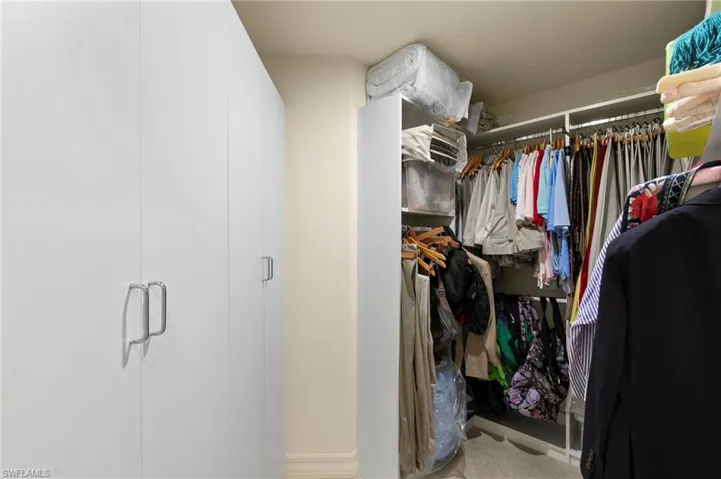 Custom closet system featuring multiple storage cabinets with integrated handles and open shelving with hanging rods