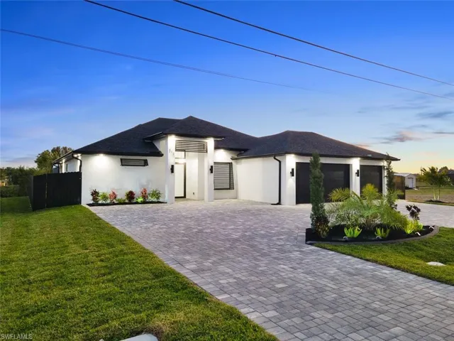 View of front of house featuring stucco siding, a front lawn, decorative driveway, fence, and an attached garage