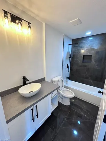 Full bathroom featuring vanity, tiled shower / bath, and toilet