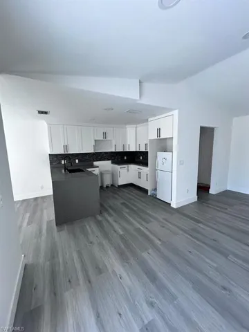 Kitchen with white refrigerator, sink, white cabinets, and decorative backsplash
