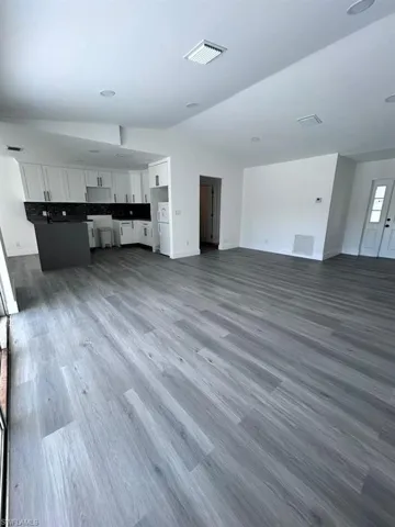 Unfurnished living room with lofted ceiling and dark wood-type flooring