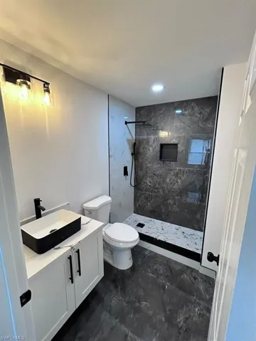 Bathroom with vanity, toilet, and tiled shower