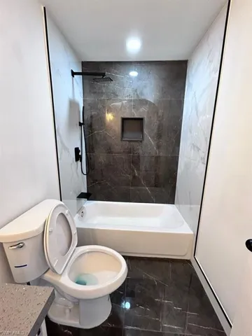 Bathroom featuring tiled shower / bath combo and toilet