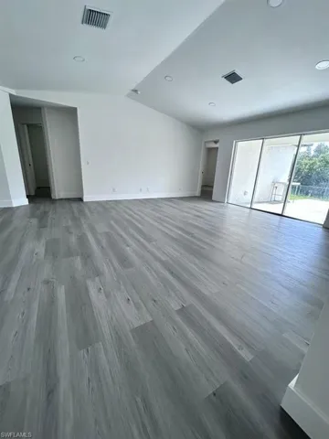 Empty room featuring hardwood / wood-style flooring and vaulted ceiling