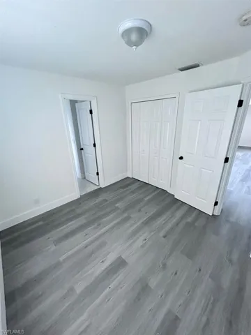 Unfurnished bedroom with dark wood-type flooring and a closet