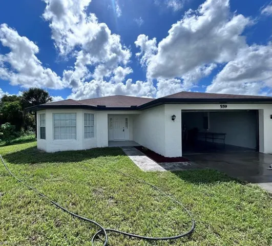 Rear view of property featuring a garage and a yard