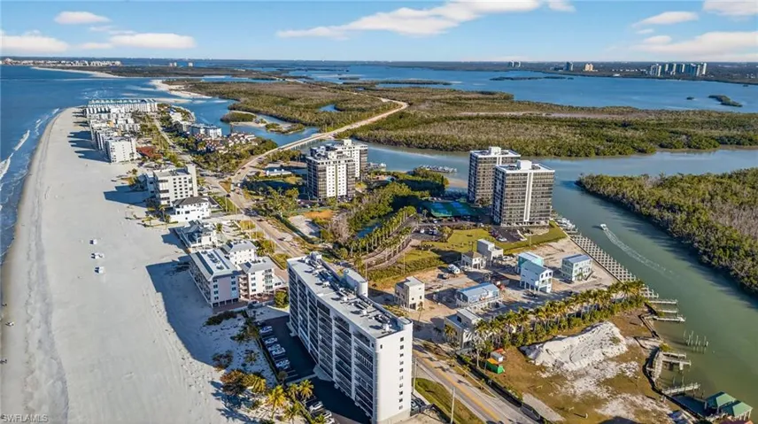 Coastal aerial perspective featuring direct beach frontage, high-rise residential architecture, proximity to natural waterways, and dense coastal vegetation