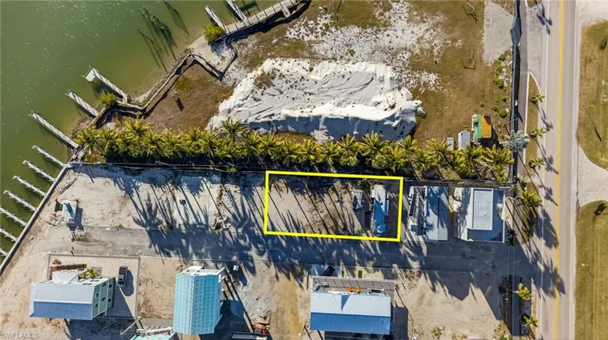 Waterfront parcel featuring direct canal access, a paved access road, and mature perimeter palm trees